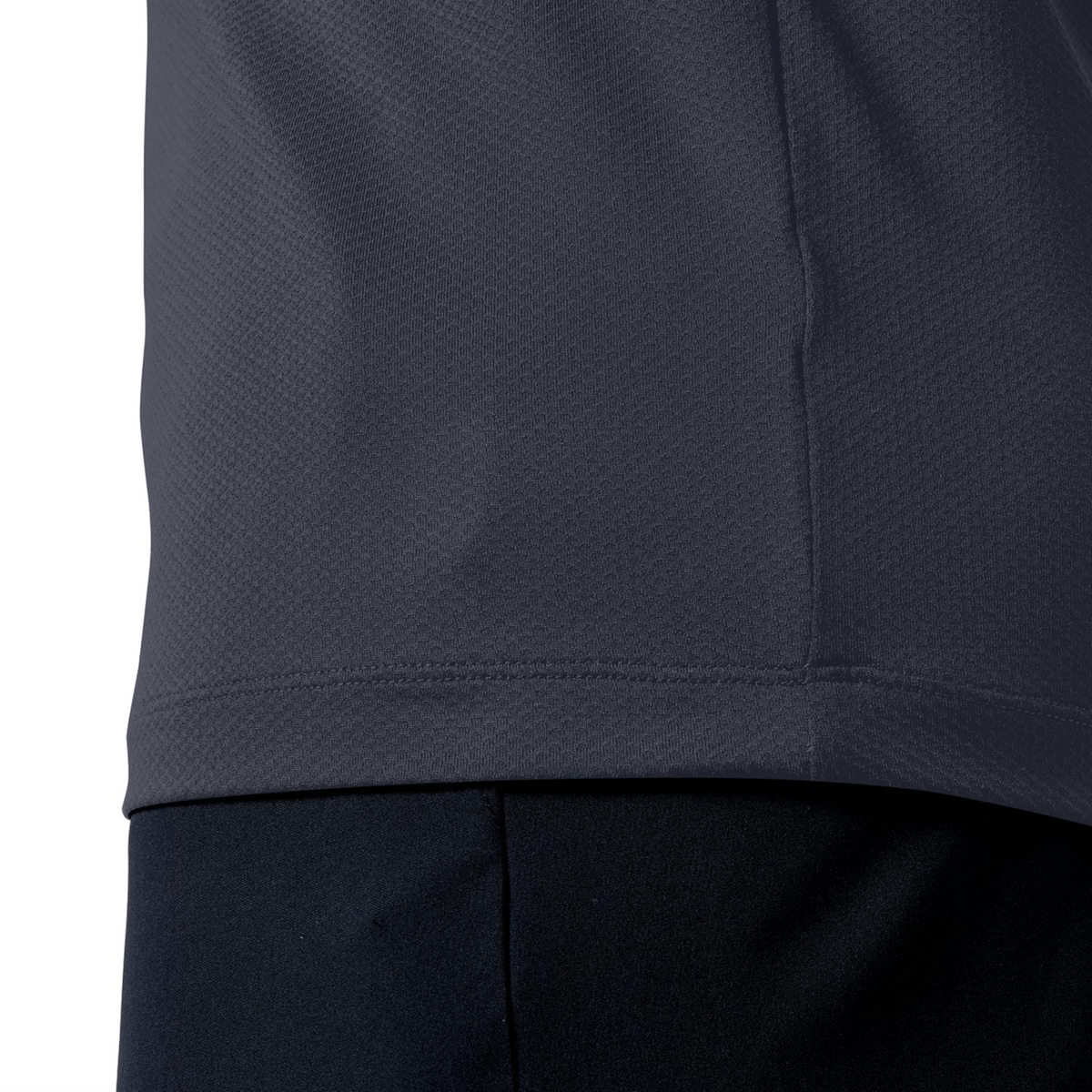 Side view of a person in a Canterbury Tempo+ Training Tee, dark gray, with black pants. The close-up highlights the moisture-wicking texture of the fabric for ultimate comfort and coolness.