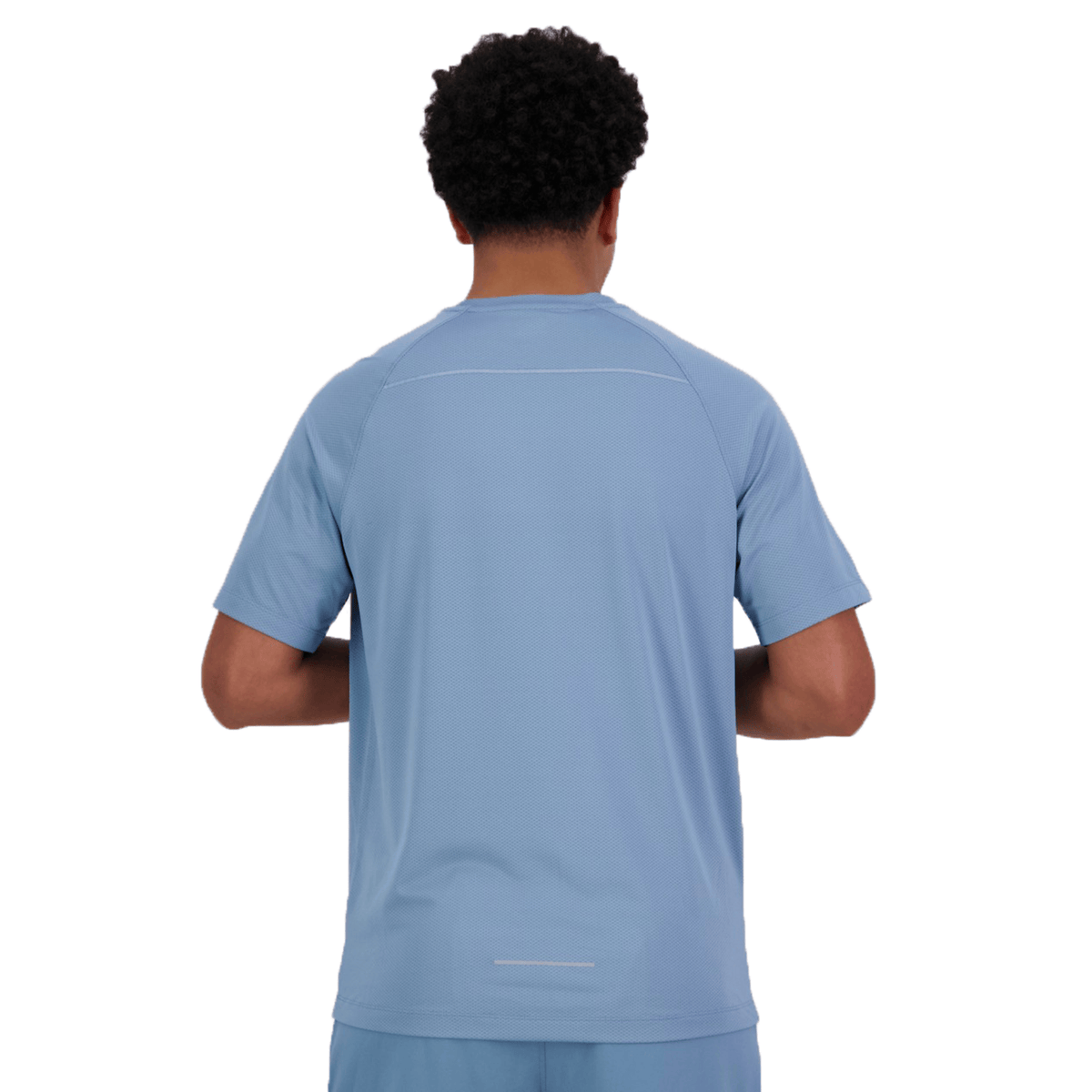 A person with curly hair faces away from the camera, wearing a Canterbury Tempo+ Training Tee in light blue and matching pants with subtle reflective details.
