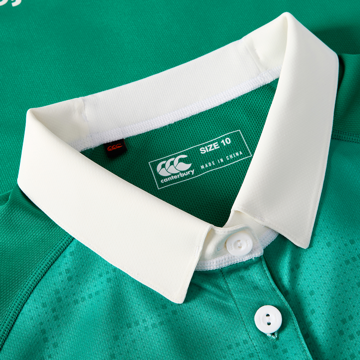 Close-up of the Canterbury Women&#39;s Ireland WIRFU 25/26 Pro Home Jersey in green, featuring a white collar with buttons and a visible size 10 label plus &quot;Made in China&quot; text inside the neckline.
