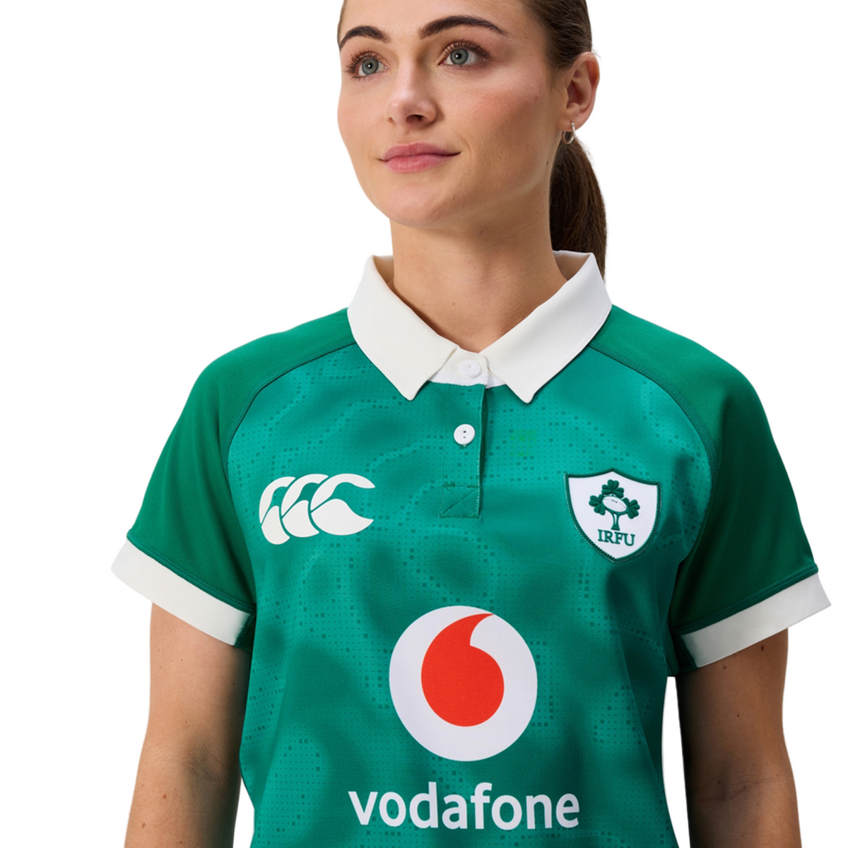 A woman stands against a plain background wearing the Women&#39;s Ireland 25/26 Home Pro Jersey by Canterbury—a green IRFU jersey with Canterbury and Vodafone logos.