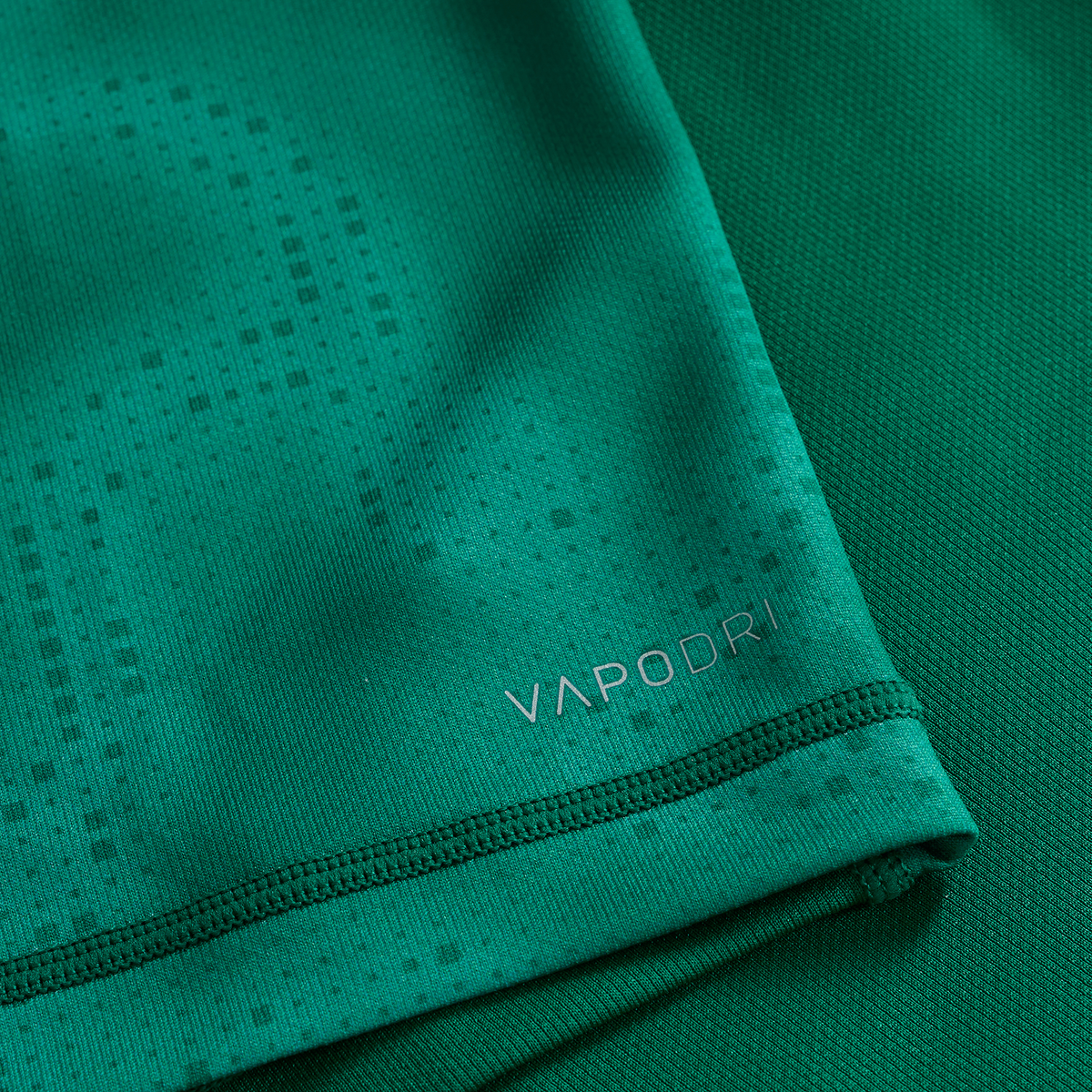 Close-up of green textured fabric from the Ireland 25/26 Home Pro Jersey by Canterbury, featuring &quot;VAPODRI&quot; printed in silver near the hem.