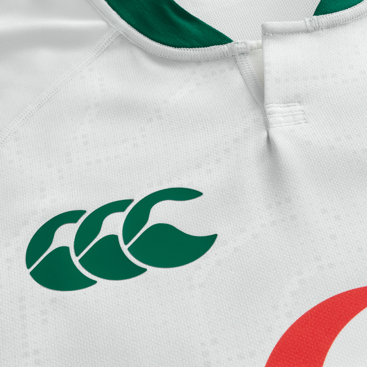 Close-up of the Ireland 25/26 Alternate Pro Jersey by Canterbury, featuring a white base, green Canterbury Vapodri logo on the left, part of a red circular design on the right, and a white collar with green lining.