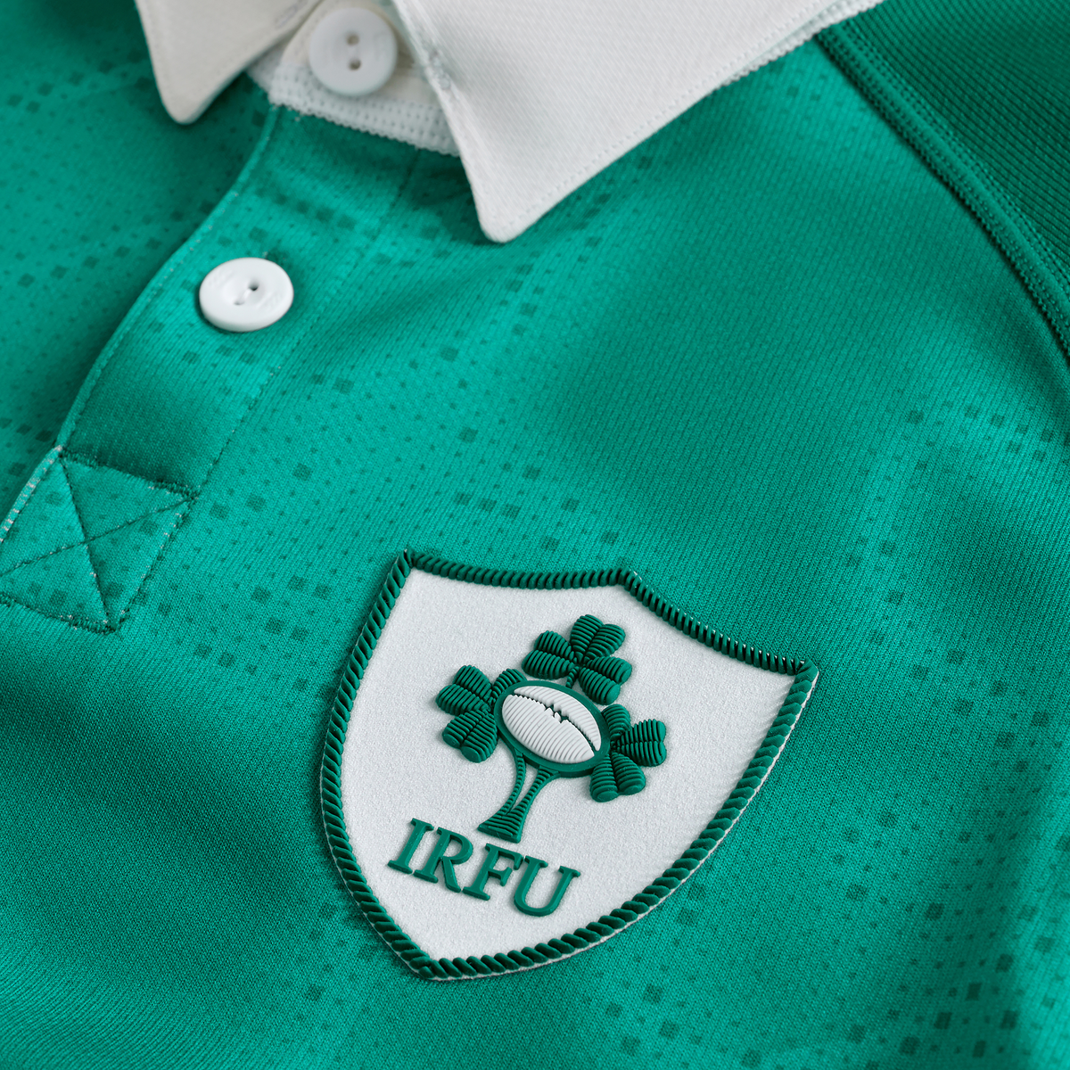 Close-up of the Youth Ireland 25/26 Home Pro Jersey by Canterbury, showcasing its green design, white collar, and the iconic IRFU crest with a shamrock and rugby ball emblem.