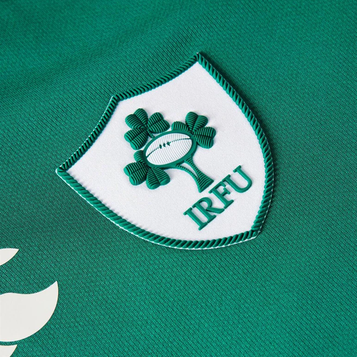Close-up of the Canterbury Women&#39;s Ireland WRWC25 Replica Home Jersey crest on green fabric—official merchandise for fans.