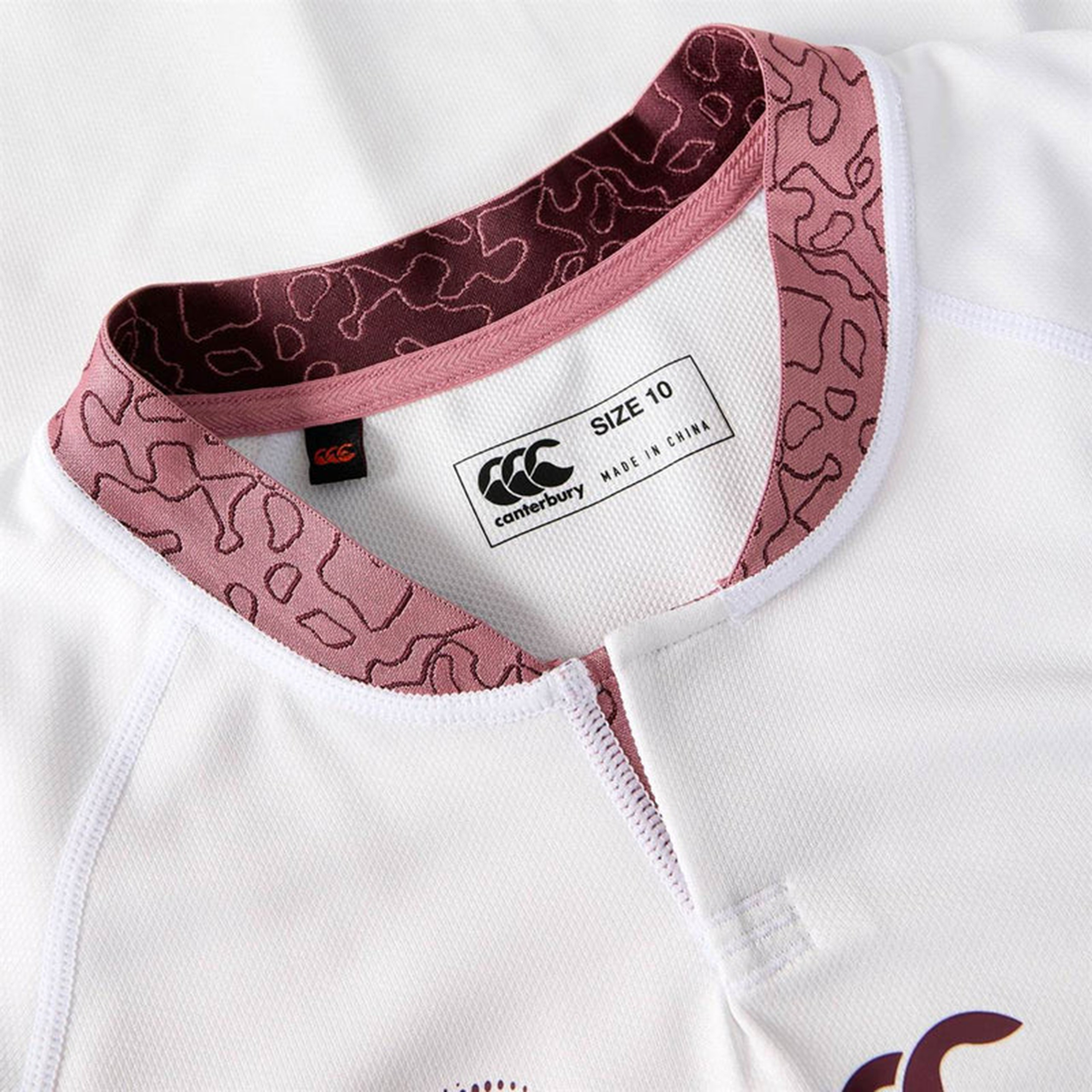 Close-up of the Women&#39;s Ireland WRWC25 Replica Alternate Jersey by Canterbury, white with a maroon patterned collar, featuring a &quot;SIZE 10&quot; and &quot;MADE IN CHINA&quot; brand tag.