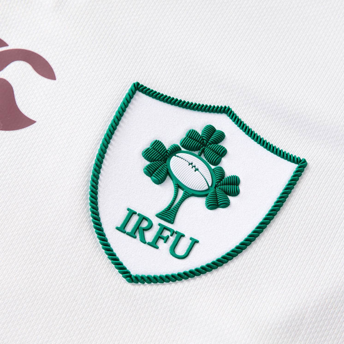 Close-up of the Canterbury Women&#39;s Ireland WRWC25 Replica Alternate Jersey, showing the IRFU logo with a green shamrock and rugby ball on white fabric, designed for the Ireland Women’s Rugby World Cup 2025 team.