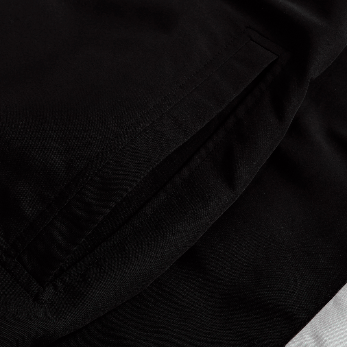 Close-up of a black fabric garment, the Canterbury Ireland 25/26 Legends 1/4 Zip Jacket, featuring a neatly stitched, slanted welt pocket.