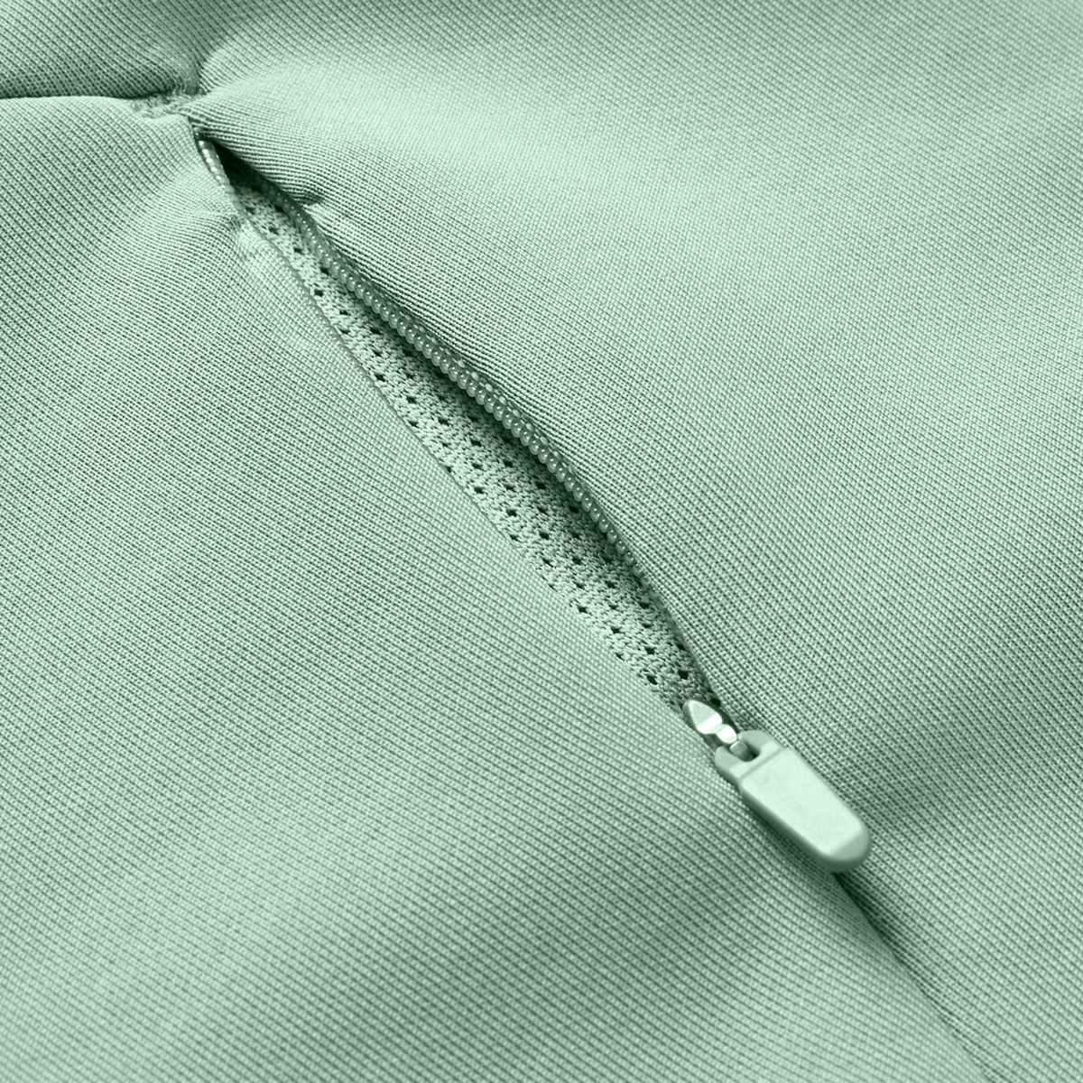 Close-up of a Canterbury Everest Zip Thru Hoodie pocket in light green by Canterbury, showing a partially open zipper and the inner lining.