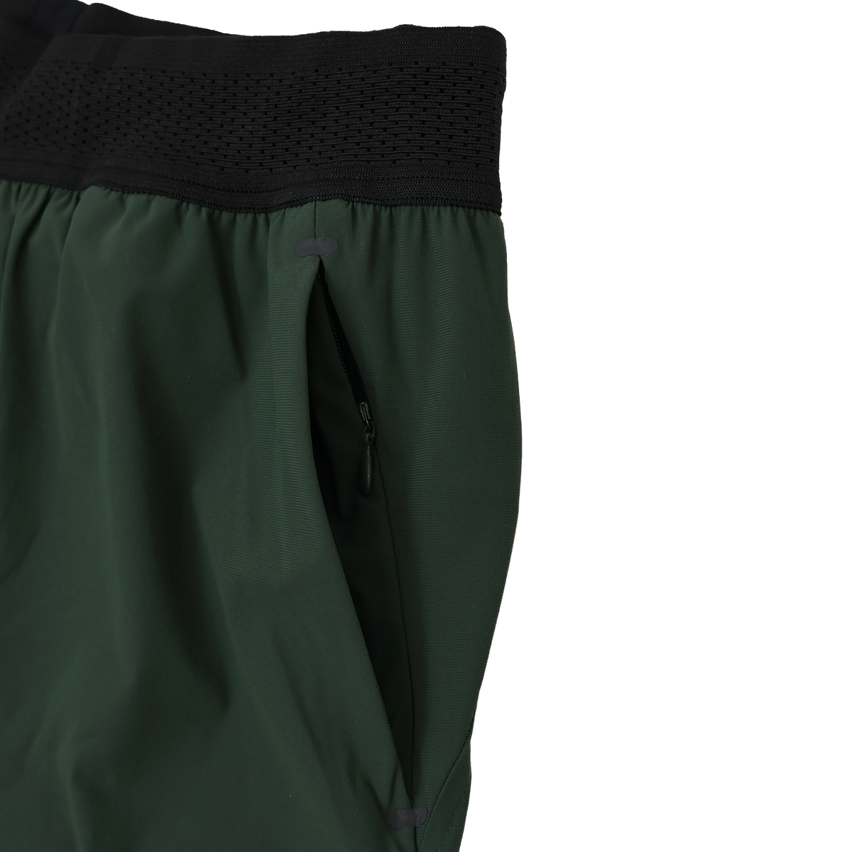 Close-up of the Canterbury Everest Woven Short 5" by Canterbury, a green training short with black elastic waistband, zippered side pocket, and four-way stretch fabric for optimal comfort.