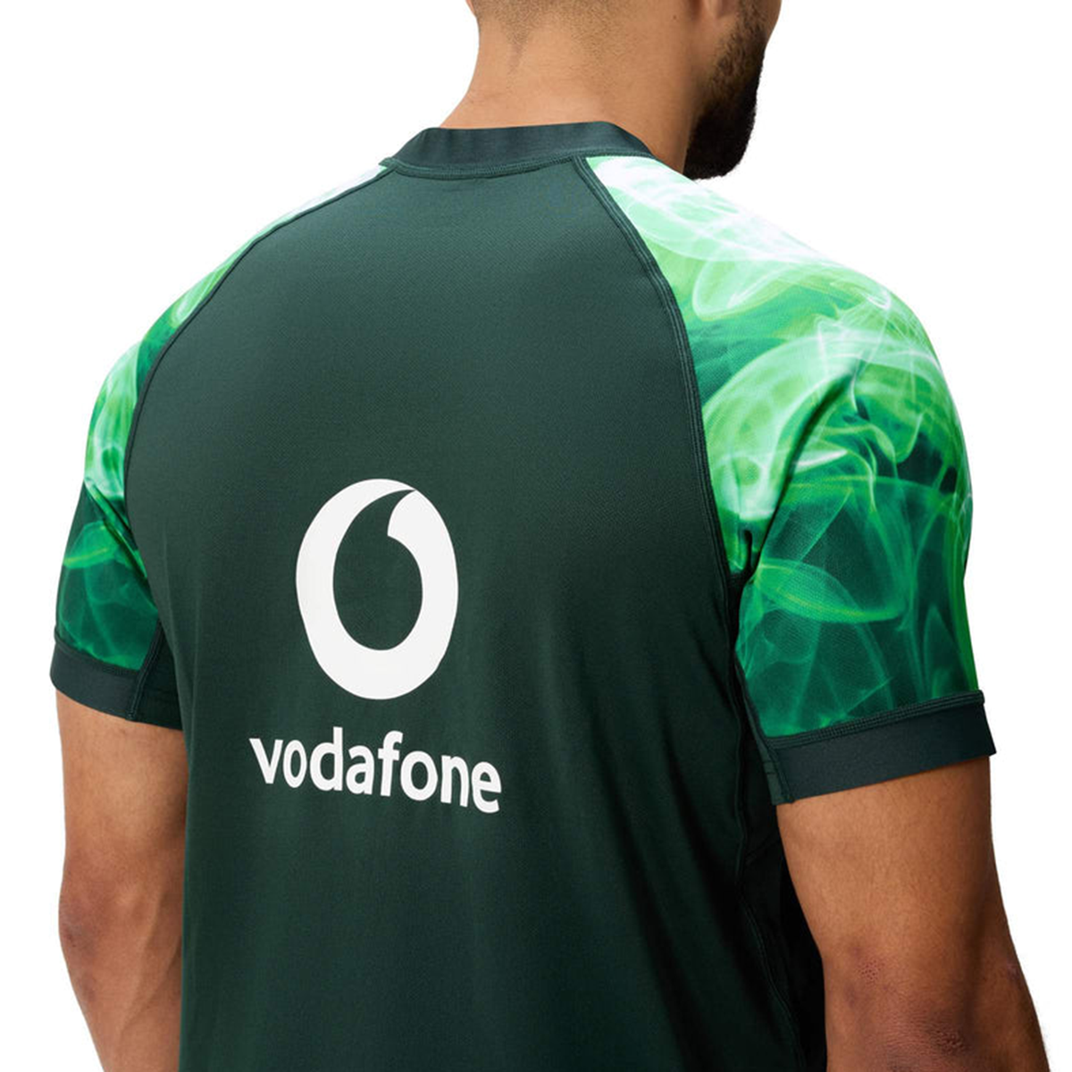 A person wears the Limited Edition Ireland "Chicago" Pro Pre-Game Jersey by Canterbury, featuring green patterned sleeves, a large white Vodafone logo on the back, and advanced VapoDri technology for comfort.