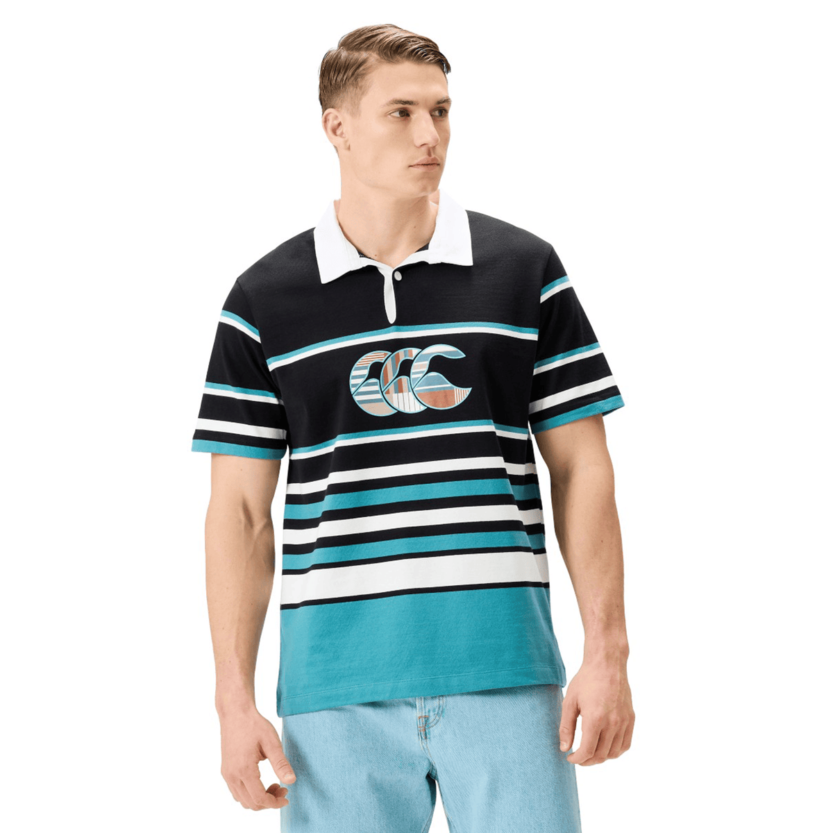 Man wears a Canterbury Uglies Short Sleeve Classic Rugby Jersey featuring horizontal black, white, and teal stripes with a bold "CCC" logo, paired with light blue jeans.