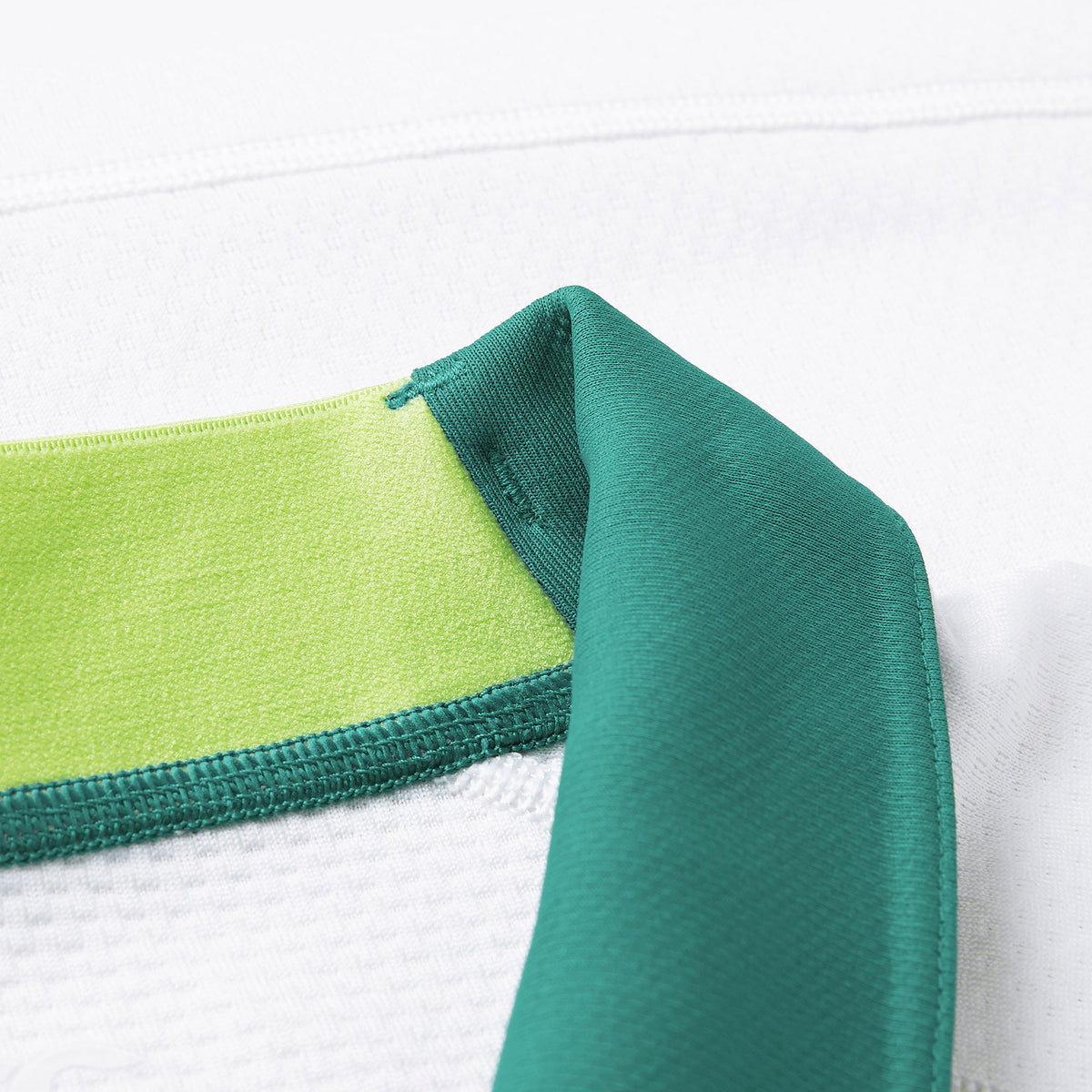 Close-up of a white textured fabric featuring a green collar and light green inner lining, with detailed stitching and material contrast—showcasing the premium craftsmanship of the Ireland 26 Alternate Test Jersey by Canterbury.