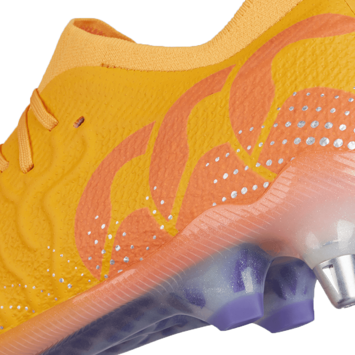 Close-up view of the Canterbury Speed Infinite Elite SG soccer cleat in Amber Yellow/Orange Crush/Mars Dust, showcasing an ultra-lightweight design with a gradient pattern and iridescent accents. It features a VAPOSKIN membrane and a metal-studded sole for enhanced grip on the field.