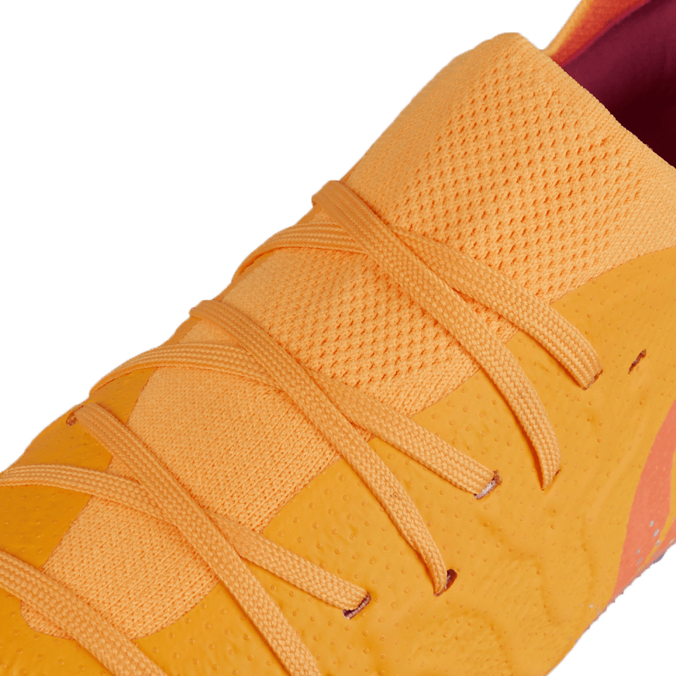 Close-up view of the Canterbury Speed Infinite Elite SG in Amber Yellow/Orange Crush/Mars Dust, featuring matching laces, a textured surface, and innovative FLIGHTBEAM technology.