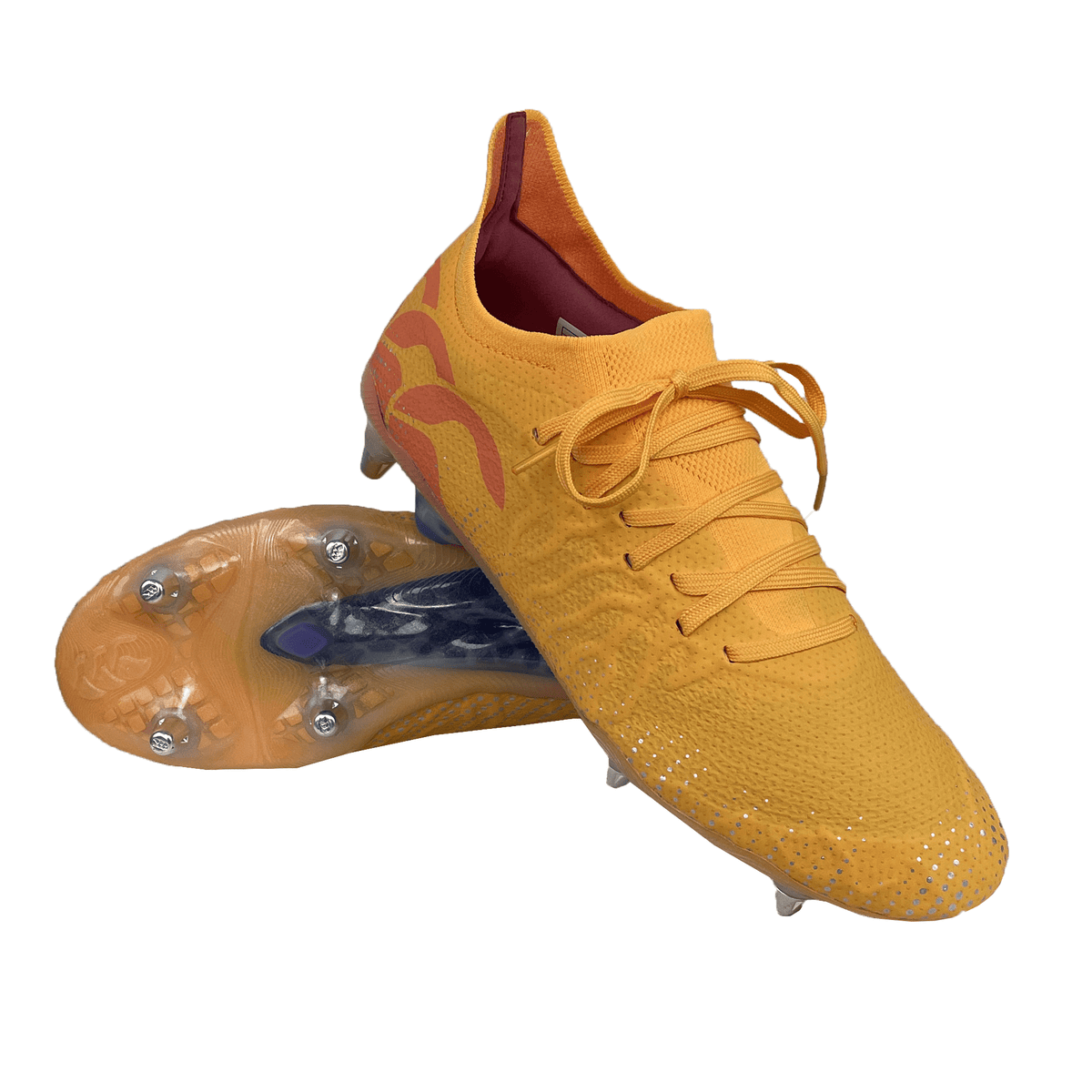 A pair of Canterbury Speed Infinite Elite SG soccer cleats in Amber Yellow with Orange Crush and Mars Dust accents, featuring laces and metal studs on the soles. Engineered with a VAPOSKIN membrane for a snug fit, one cleat is placed atop the other.