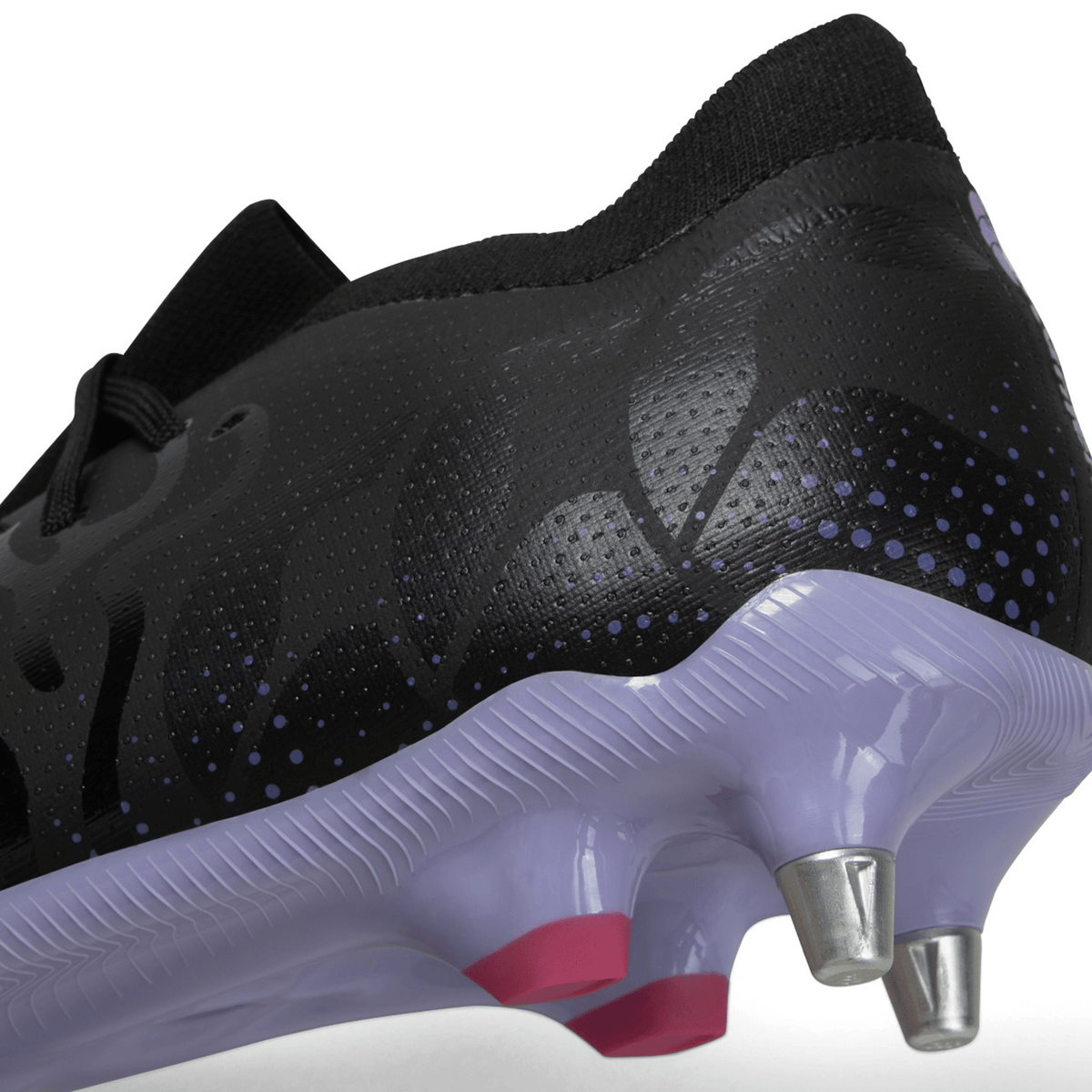 Close-up view of a black athletic shoe, the Canterbury Speed Infinite Pro SG - Black/Verbena, with a textured design and a translucent sole featuring metallic cleats for enhanced kicking accuracy.