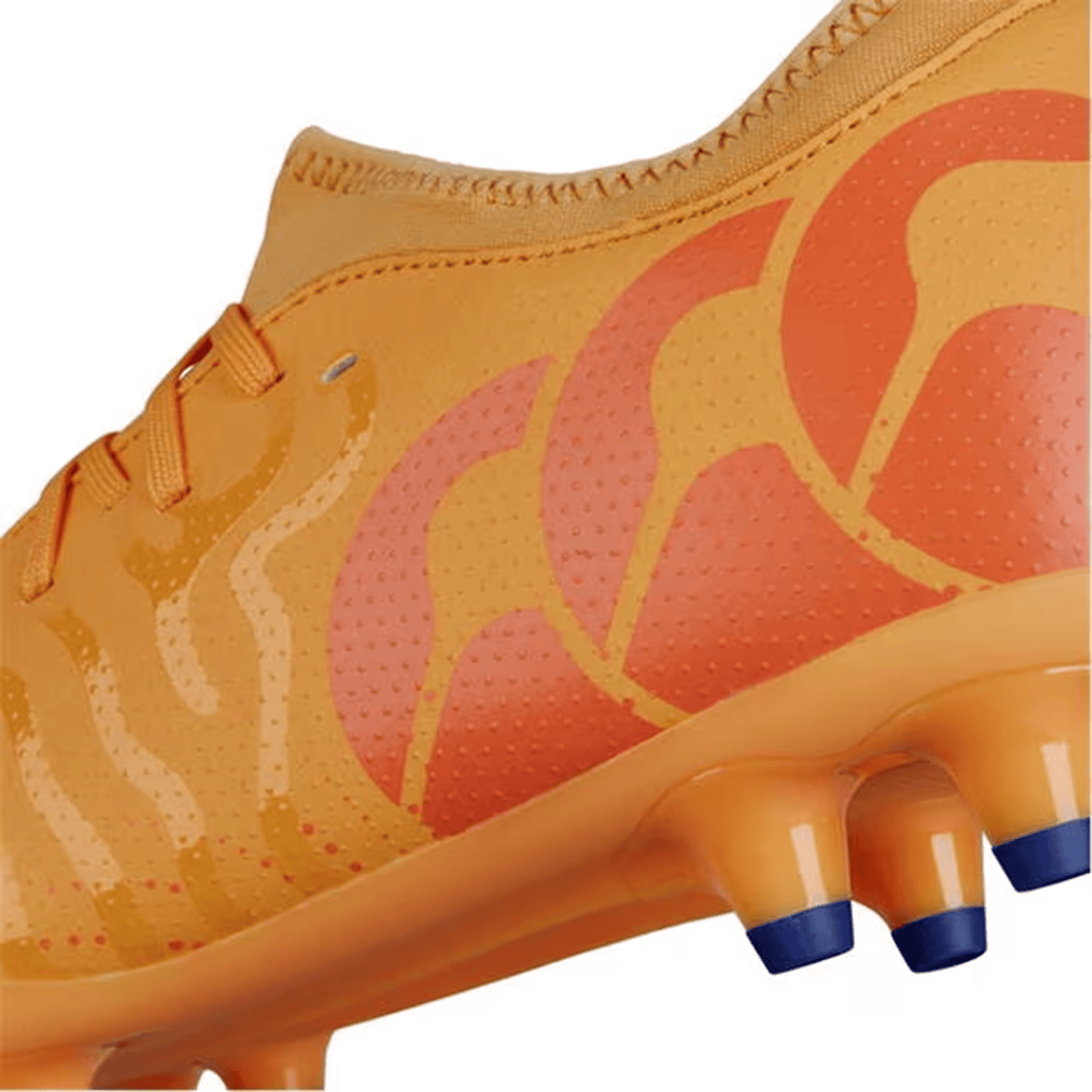 Close-up of an amber yellow soccer cleat with orange crush and mars dust wave patterns, featuring blue studs on the sole. The lightweight design boasts a synthetic upper, resembling the sleek style of Canterbury Speed Infinite Team FG boots by Canterbury.