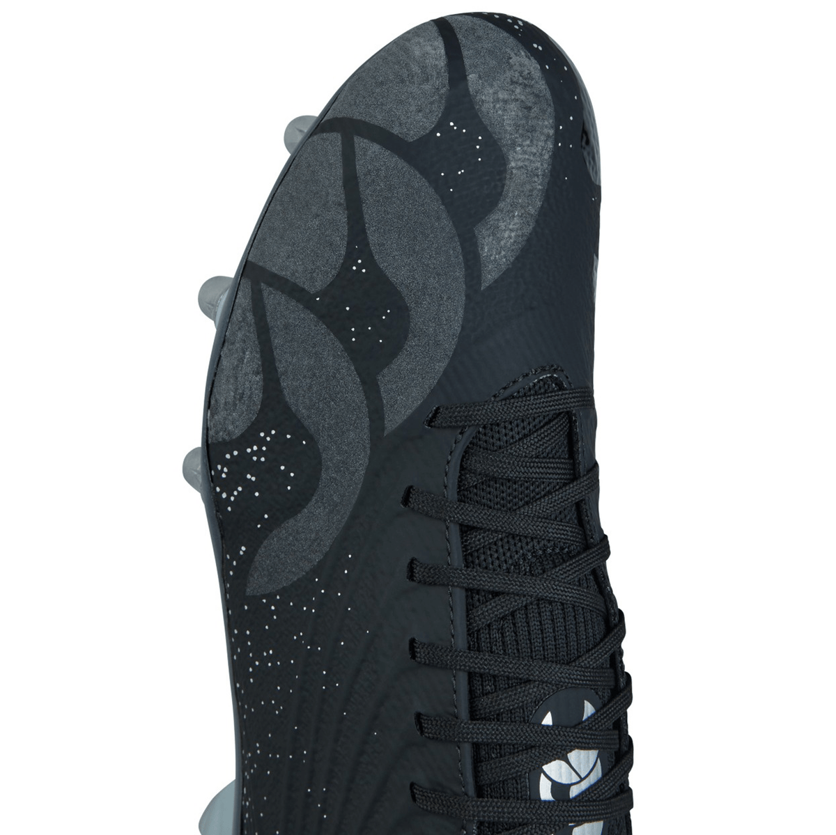 Close-up of a Canterbury Stampede Groundbreak Elite SG Cleat in Black/Silver Metallic with a textured design and laces. The top features a pattern of curved lines and small white specks.