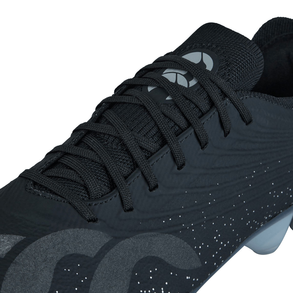 Close-up view of a black sports shoe with black laces, featuring a patterned design and a logo near the tongue. This Canterbury Stampede Groundbreak Elite SG - Black/Silver Metallic model is perfect for tough terrains.