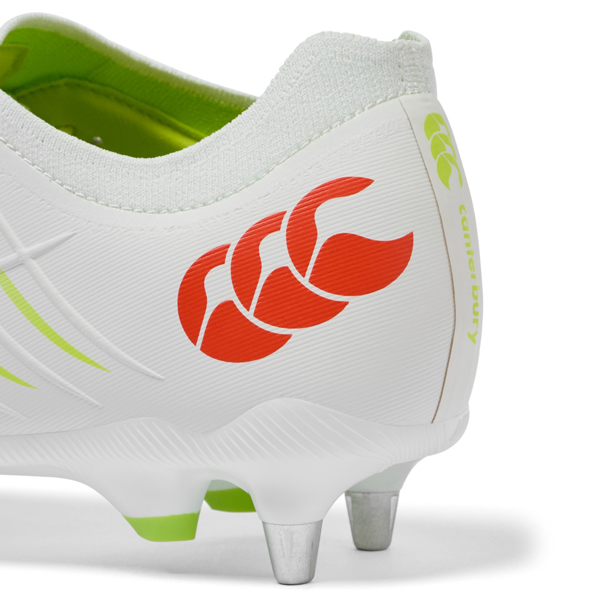 Close-up of the heel on a Canterbury Phoenix 2.0 Pro SG rugby boot in Snow White/Tangerine Tango, highlighting the orange Canterbury logo, lime green interior, and metal soft ground studs.