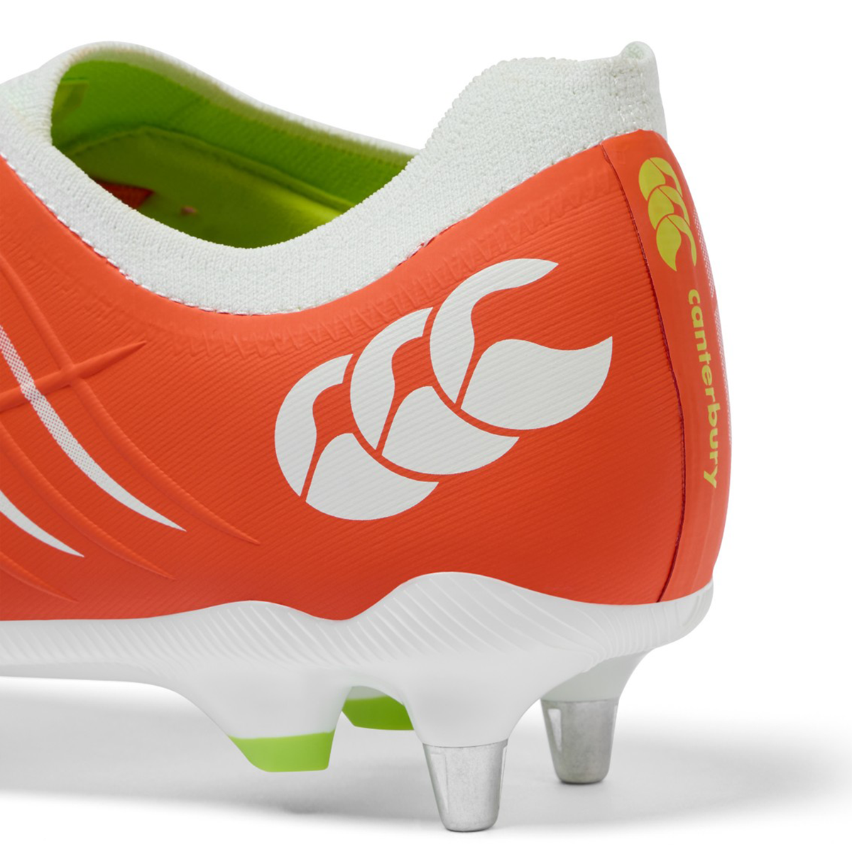 Close-up of the heel of the Canterbury Phoenix 2.0 Pro SG rugby boot in Tangerine Tango/Snow White, featuring white and yellow detailing, metal studs, and a Canterbury logo on the side.
