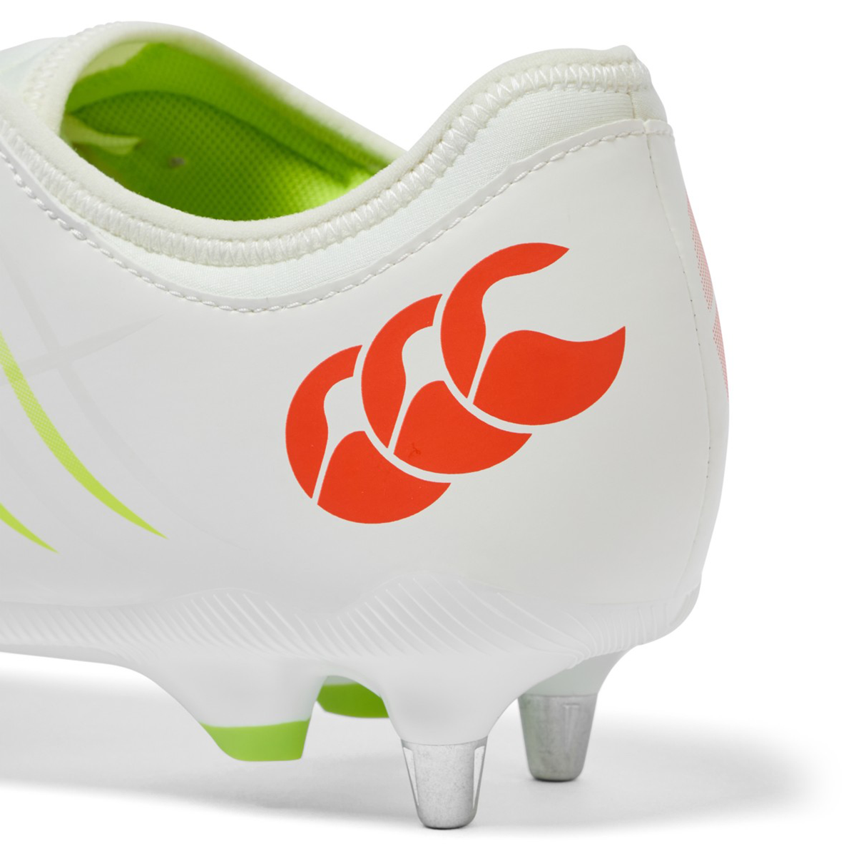 Close-up of the heel of the Canterbury Phoenix 2.0 Team SG rugby boot in Snow White/Tangerine Tango, featuring metal studs, a lime green interior, and a red Canterbury logo on the side.