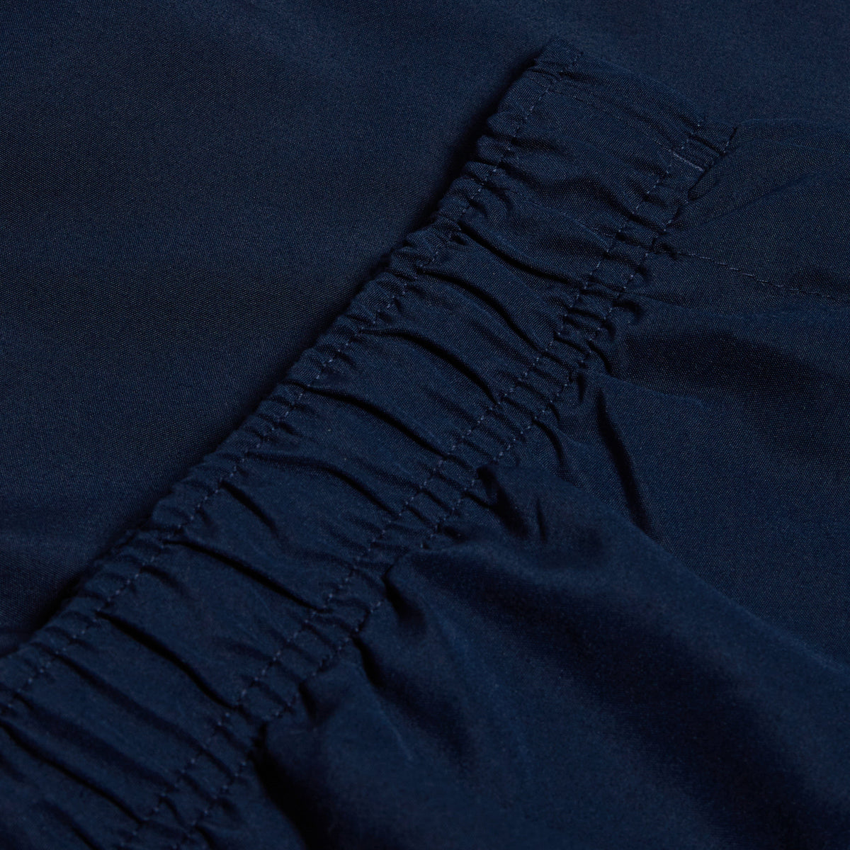 Close-up of dark blue fabric with gathered elastic stitching, reminiscent of a Canterbury logo design on the Women&#39;s Canterbury Open Hem Stadium Pant.