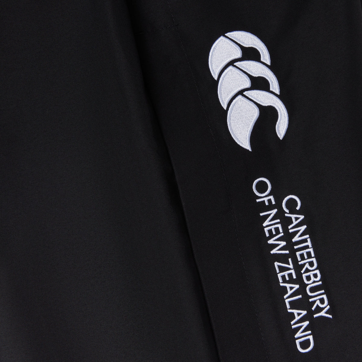 Close-up of black fabric with &quot;Canterbury&quot; branding and a white logo featuring three stylized shapes. The Women&#39;s Canterbury Open Hem Stadium Pant is perfect for rugby training, offering full-length leg zips for easy wear and versatility.