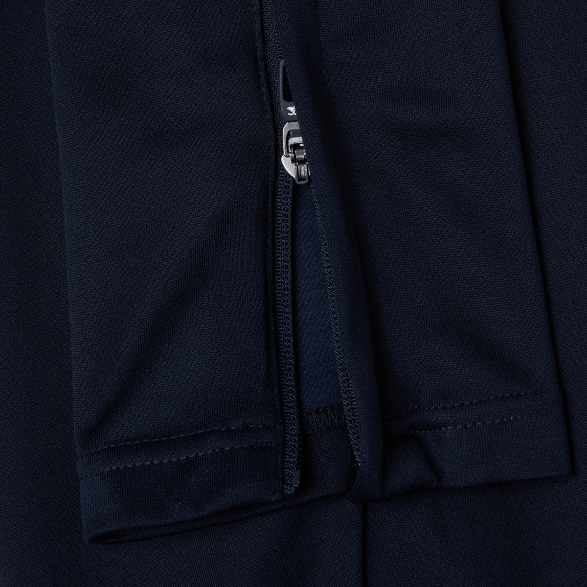 Close-up of the Canterbury Stretch Tapered Pant in navy blue, featuring a partially unzipped seam showcasing metal teeth and fabric stitching; an ideal choice for a workout with its quick-dry feature.