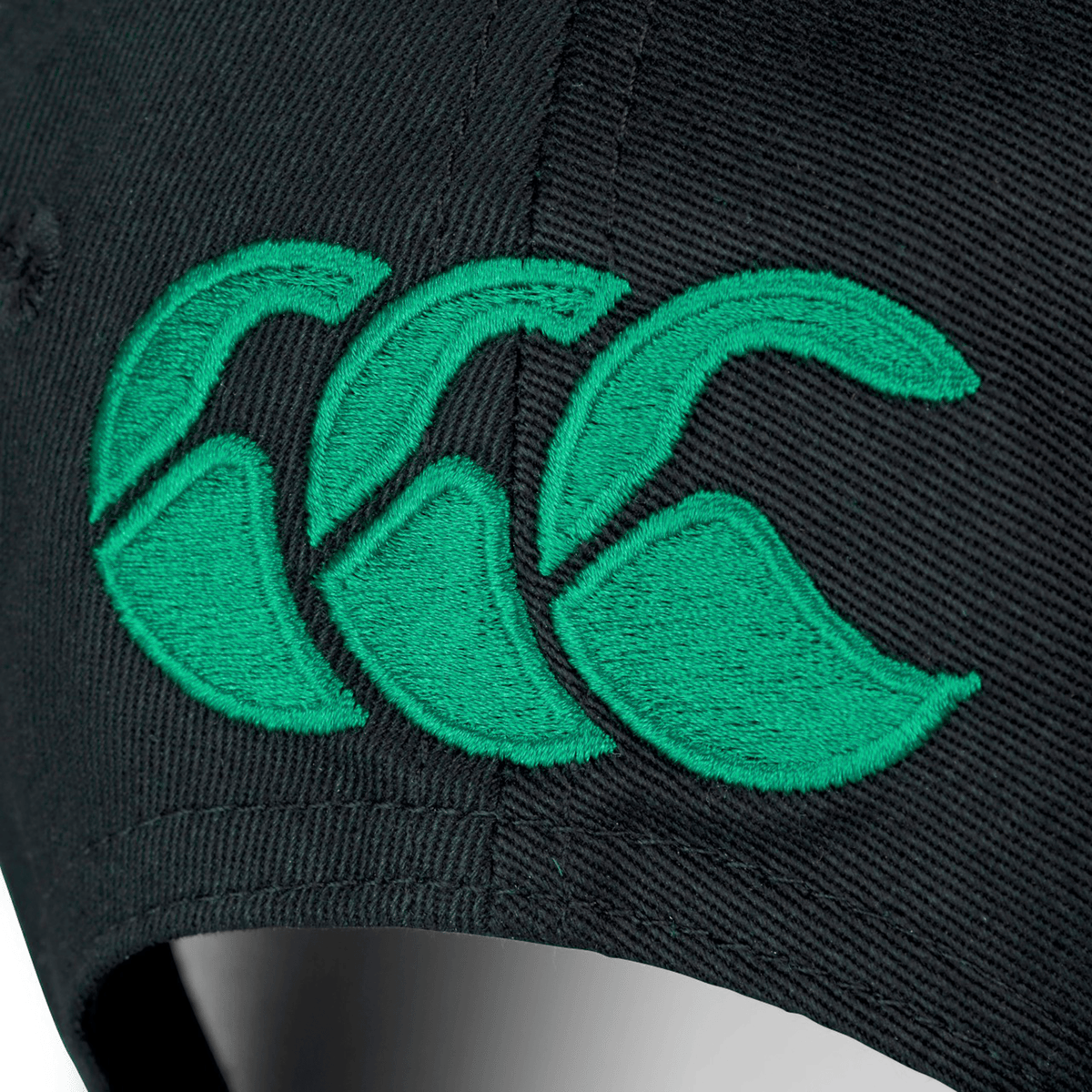 Close-up of the Ireland 25/26 Drill Cap by Canterbury, a black cap featuring Canterbury’s green embroidered logo with three overlapping stylized "C"s.
