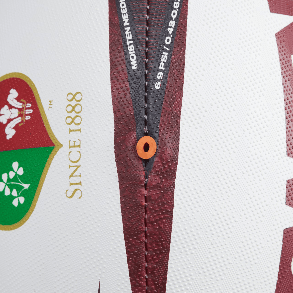 Close-up view of the British &amp; Irish Lions 2025 Mentre Sponsor Ball by Canterbury, crafted from synthetic rubber and showcasing a red seam. The ball features logos and the text "Since 1888," with its inflation valve centrally aligned between the stitching, capturing the essence of the British &amp; Irish Lions spirit.