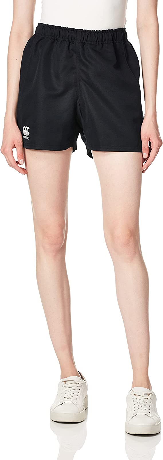 A person is wearing Canterbury&#39;s Women&#39;s Advantage Pro Rugby Shorts against a plain background. The black shorts made from sleek polyester offer moisture management for ultimate comfort, paired with a white top and sneakers.